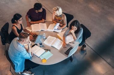 Estudiantes de medicina trabajando en grupo con libros y laptop en una mesa de estudio